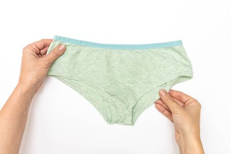 Woman taking pills, female hands holding a blister of blue pills, capsules and a glass of water on white table.の写真素材