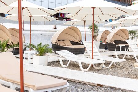 Many sun beds and umbrellas on a seashore at luxury resort, sunbathing and relaxing concept.の写真素材