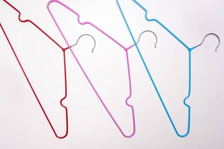 Many colorful metal wire coat, clothes hangers on white background.の写真素材