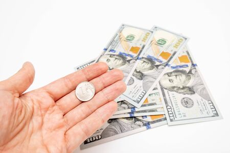 A hand holding one ruble coin and american dollar banknotes on background, ruble devaluation and...