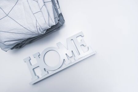 A stack of cozy home textile in shades of gray bed linen, bedding with the sign home near it.の写真素材