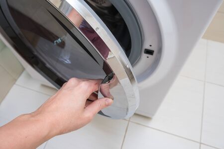 A person opening washing machine in order to wash linen and clothes, laundry concept.