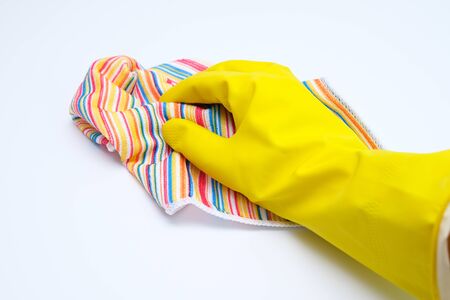 Hand in yellow rubber glove wiping dust with microfiber cloth, cleaning up the house concept, white background.の写真素材