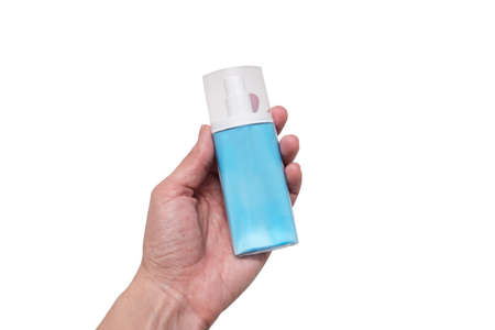 A hand holding blue plastic conteiner, bottle of moisturising cream, lotion with dosator and cap on...