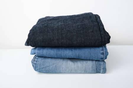 Different kinds of blue stacked jeans, denim on white background.の写真素材