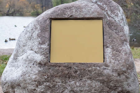 A big rock stone with an empty signboard on it with copy space.