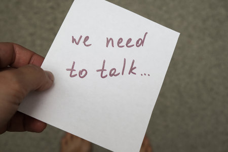 Woman holding a piece of paper with hand written frase, message We need to talk, communication problems in family between husband and wife.の写真素材