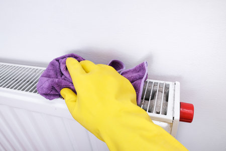 Radiator and house cleaning, hand in yellow rubber gloves wiping and washing central heating radiator with microfiber cloth.の写真素材