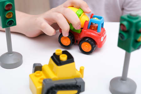 A boy playing toy cars on a white table