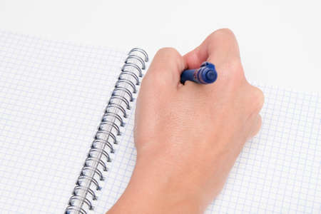 Writing notes or planning a schedule on blank spiral notebook, hand using a pen on a checkered blank paper.の写真素材