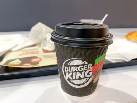 Moscow, Russia - October 12, 2021: A paper disposable takeout cup of coffee on a table in Burger King fastfood restaurantのeditorial素材