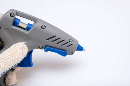 Hand holding an adhesive thermal glue gun for fixing parts, hobby and diy concept.の写真素材