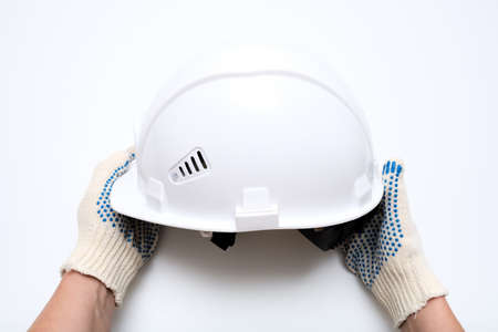 Hands of a worker, builder holding a white protective hard hat, safety helmet against white...