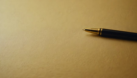 An office supply, a ball pen, is resting on a sheet of stationery. The writing instrument accessory is made of metal and sits on top of wood paperの素材