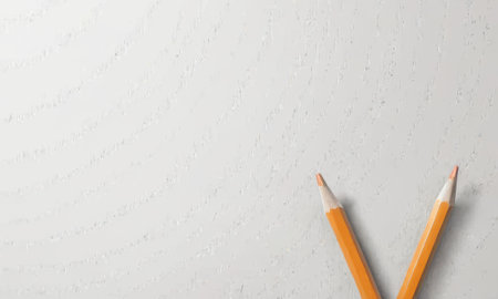 Two sharp yellow pencils form a subtle V against a textured white canvas, a minimalists approach to art. Their simplicity speaks to the endless potential in a single line.の素材