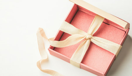 Gift box with pink ribbon on a soft white backgroundの素材