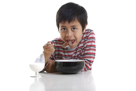 A young boy eating cereal and milk for breakfastの写真素材