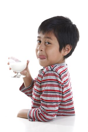 A young boy licking his lips while drinking a glass of milkの写真素材