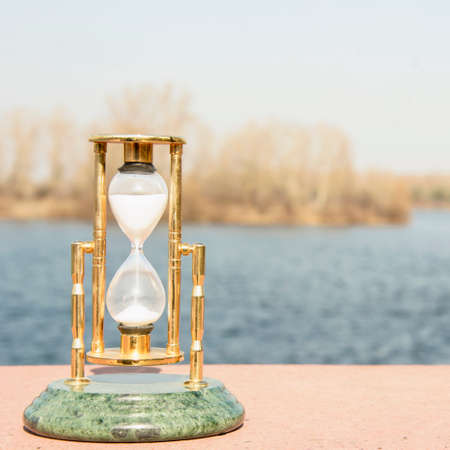 Glass beautiful hourglass on the background of beautiful nature