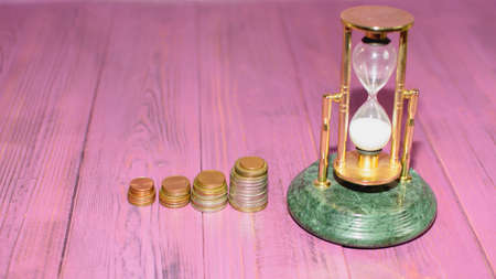 Sand glass beautiful clock with accessories on a pink backgroundの写真素材