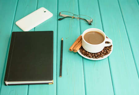 On the office table, business supplies, coffee, telephone, glasses, calculator and hourglass with a notebookの写真素材