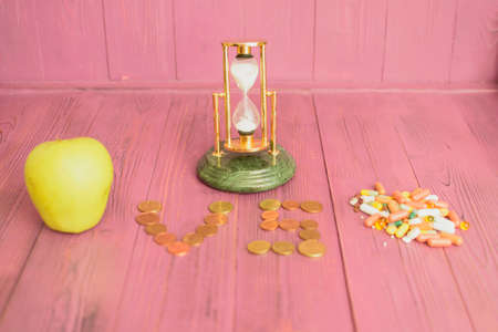 On the background of a pink background, a clock, an apple, medicines and money