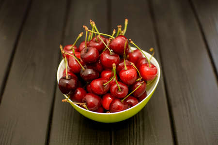 Many ripe cherries on a beautiful background in a plateの写真素材