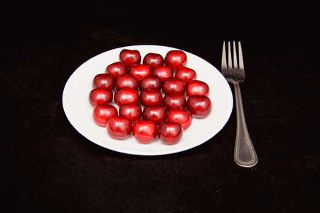 Many ripe cherries on a beautiful background in a plateの写真素材