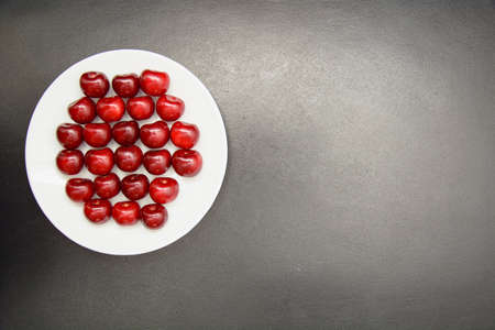 Many ripe cherries on a beautiful background in a plateの写真素材