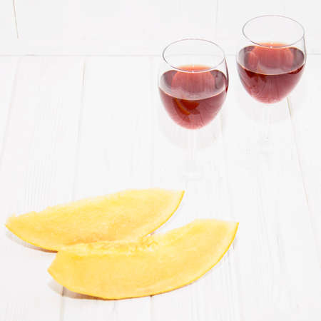 Glass of red wine and melon on a light backgroundの写真素材