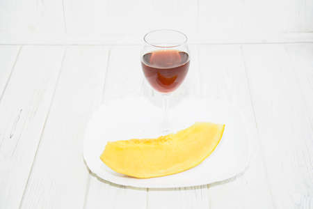 Glass of red wine and melon on a light backgroundの写真素材