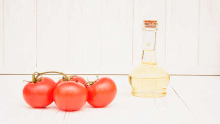 Glass bottle of fresh fragrant oil and delicious juicy ripe fresh tomatoes on a beautiful backgroundの写真素材