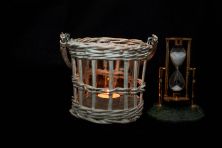 candle light and hour glass on black background, time passing concept