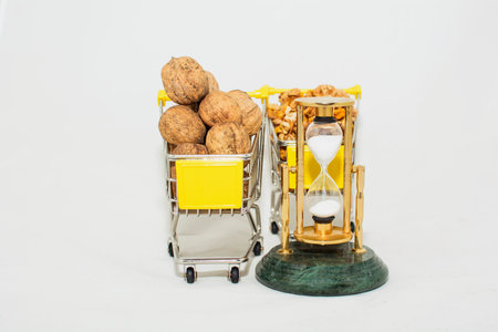 hourglass and walnuts in a shopping cart on a white backgroundの写真素材