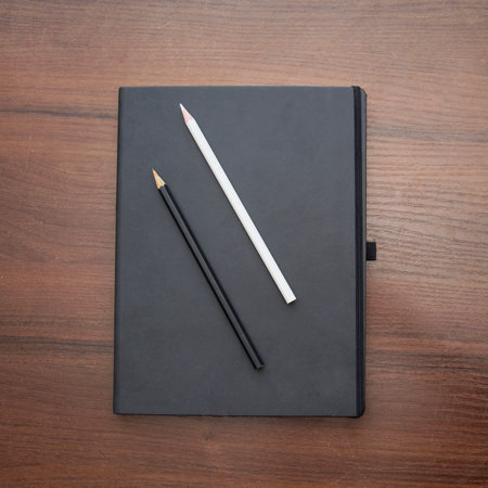 Top view of black notebook with pencil on wooden table. Back to school concept.