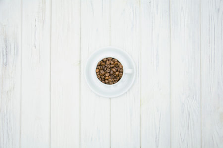 Coffee beans in a white cup on a white wooden backgroundの写真素材