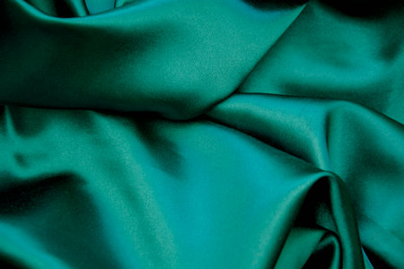 Green satin fabric texture background with shiny folds. close up.の写真素材