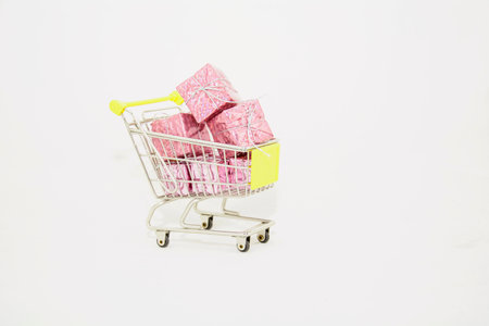 Small shopping cart with pink gift boxes on white background. shopping concept.の写真素材