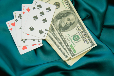 dollars and playing cards on a blue satin cloth background