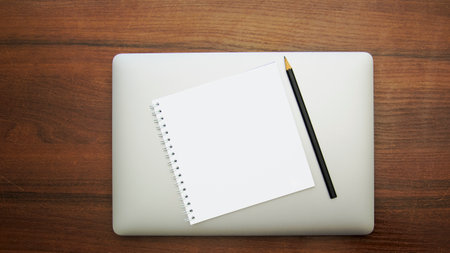 Blank notebook and pencil on wooden table background. View from aboveの写真素材