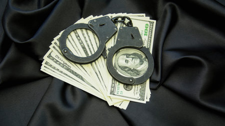 Handcuffs and money on a black satin background close upの写真素材
