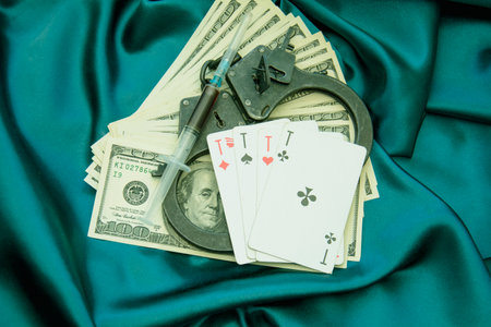 Syringe, handcuffs, money and cards on blue satin backgroundの写真素材