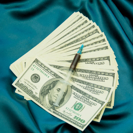 Syringe and money on blue satin background with copy space.