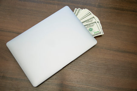 Laptop and dollars on a wooden table. top view with copy spaceの写真素材