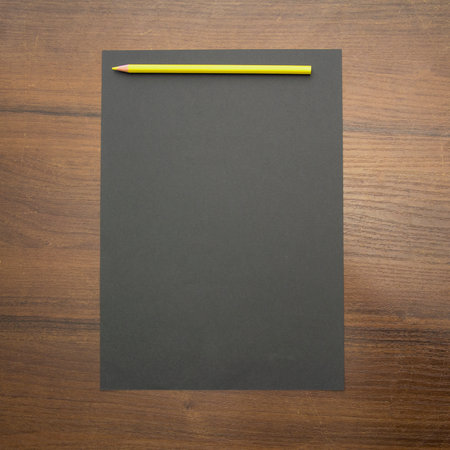 Black notepad with yellow pencil on wooden background. top view.の写真素材