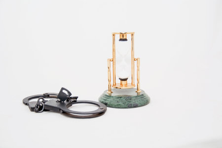 Hourglass and handcuffs on a white background, closeup of photo