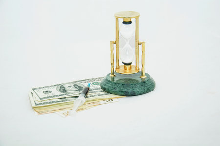 Hourglass and money on white background. Time is money concept.の写真素材