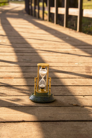 Hourglass on wooden walkway in the park. Time concept.の写真素材