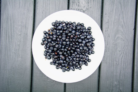 Blueberries in a white plate on a black wooden background. Top view.の写真素材