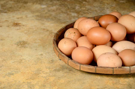 Fresh eggs in basket on concrete floorの写真素材